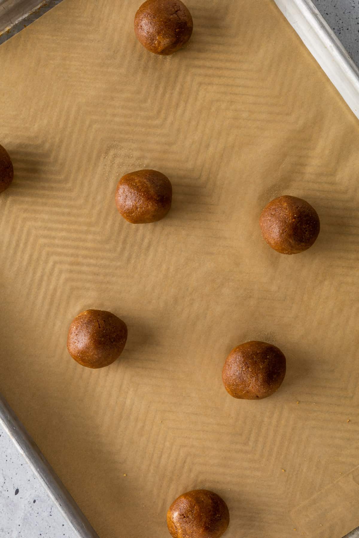 Rounded balls of cookie dough on a parchment-lined tray.
