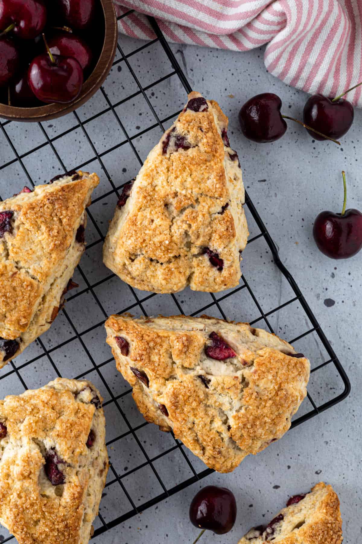 An array of cherry scones on a wire cooling rack.