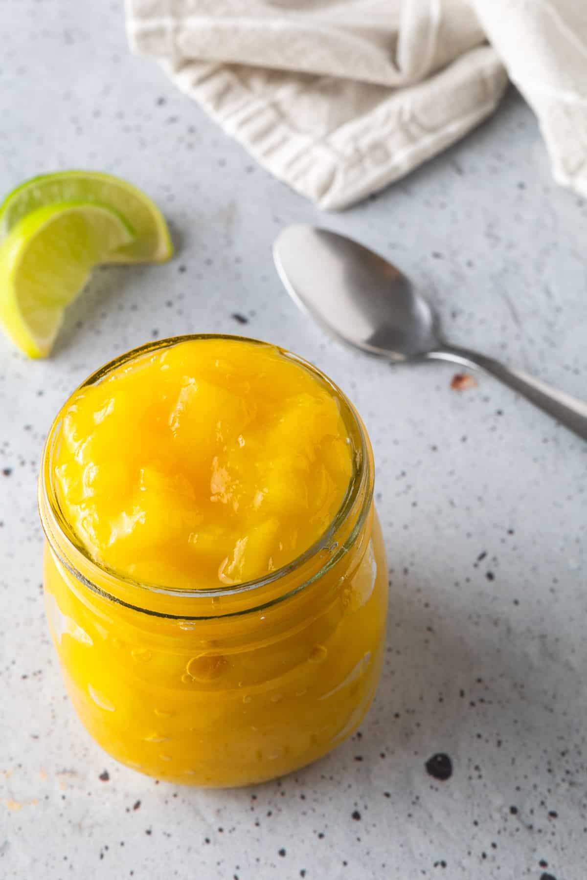 A jar of mango compote with a spoon.