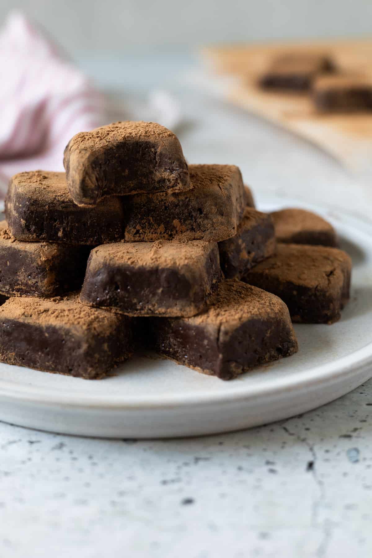 A plate of 2-ingredient truffles, one with a bite taken out of it.