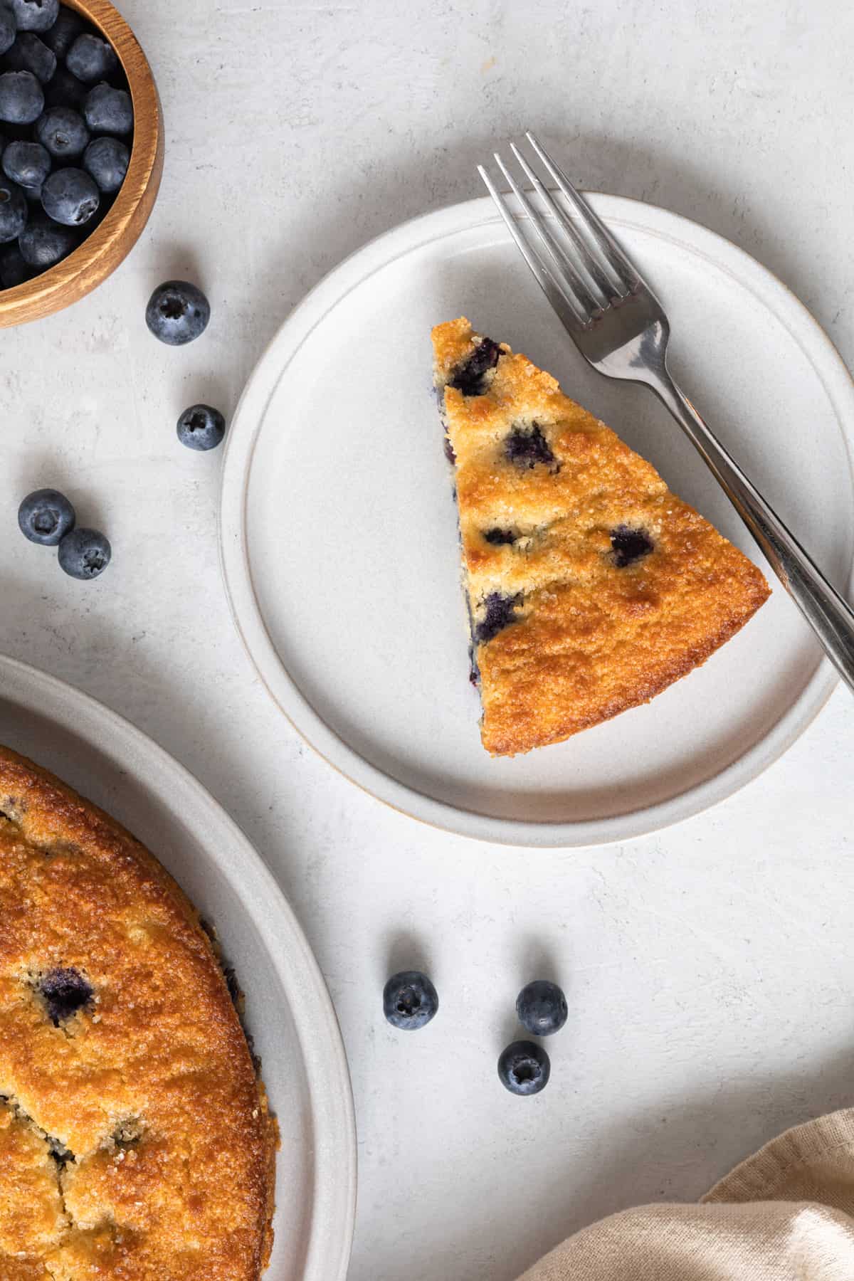A slice of low carb cake with a fork and blueberries.