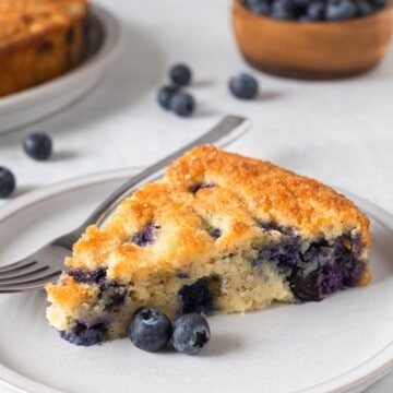 A slice of low carb blueberry cake on a small plate with a fork.