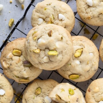 An array of pistachio white chocolate cookies on a wire cooling rack.