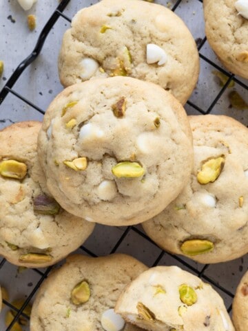 An array of pistachio white chocolate cookies on a wire cooling rack.