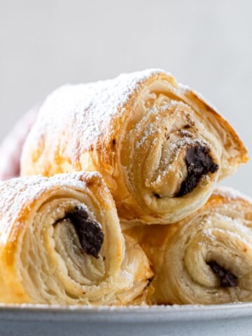 A few puff pastry chocolate croissants on a plate.