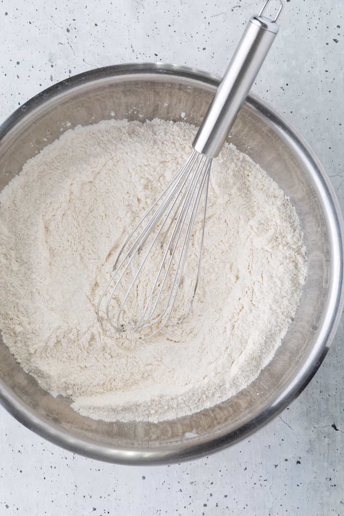 The dry ingredients in a medium bowl with a whisk.