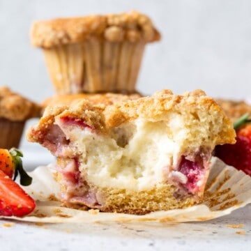 Half of an unwrapped cream cheese-filled strawberry muffin.
