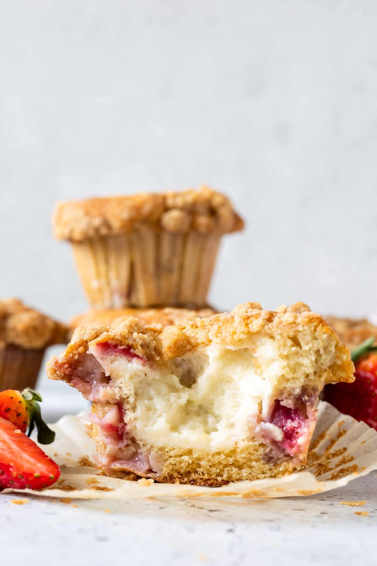 Half of an unwrapped cream cheese-filled strawberry muffin.