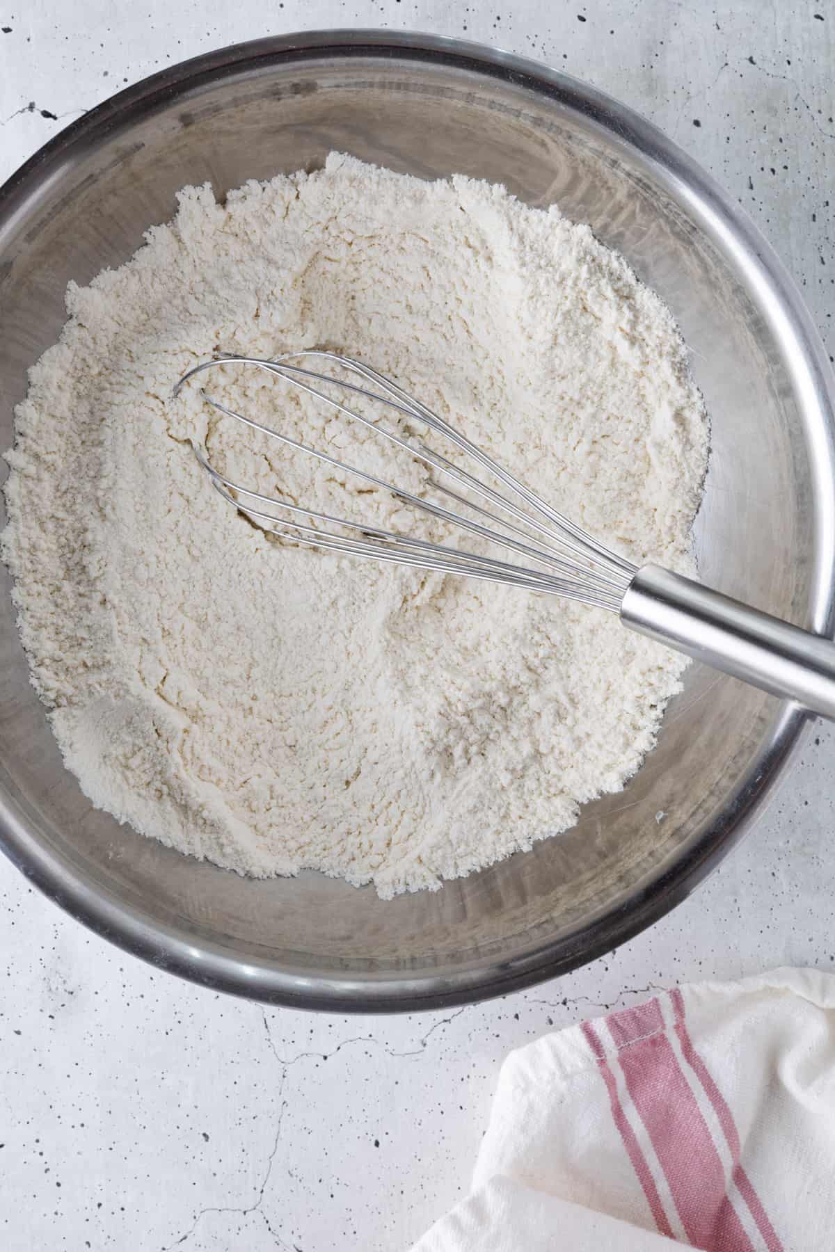 The dry ingredients in a bowl with a whisk.