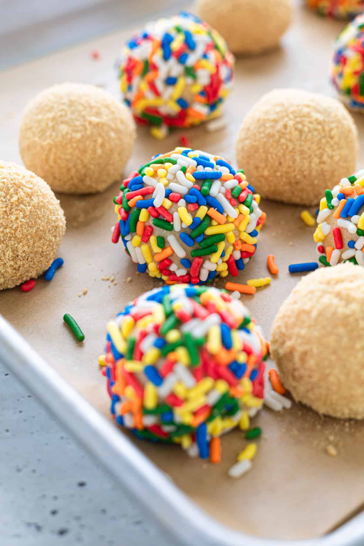 Cheesecake balls on a parchment-lined tray.