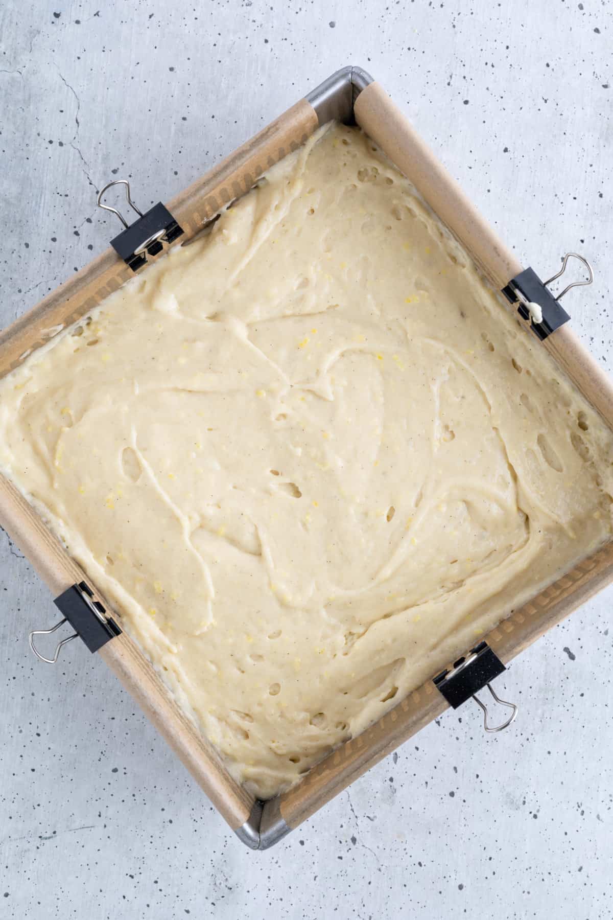 Cake batter spread into a parchment-lined cake pan.