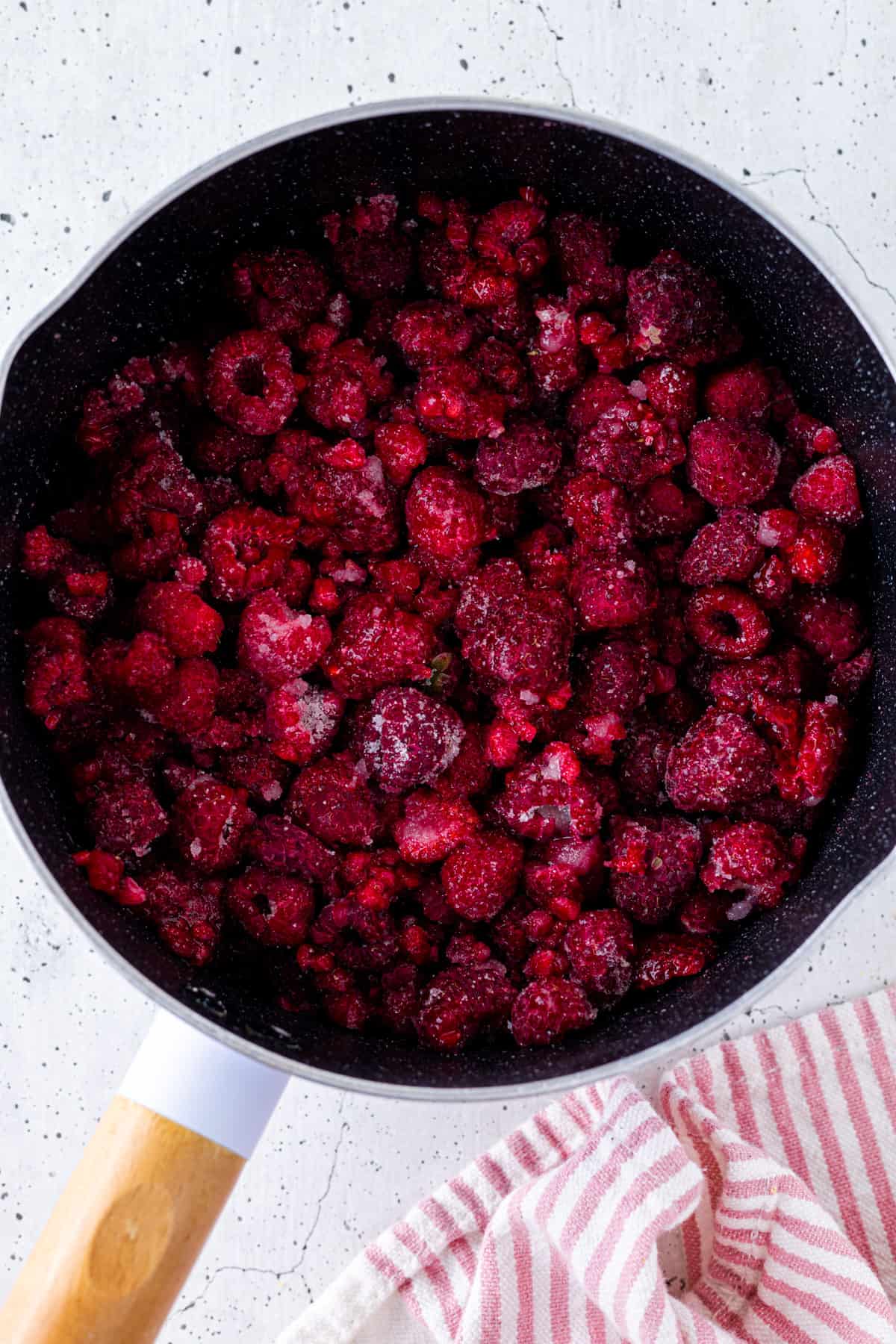 Raspberries tossed in sugar and lemon juice in a saucepan.