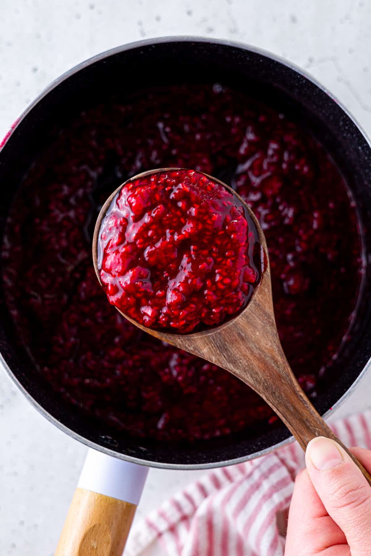 A saucepan and wooden spoon filled with compote.