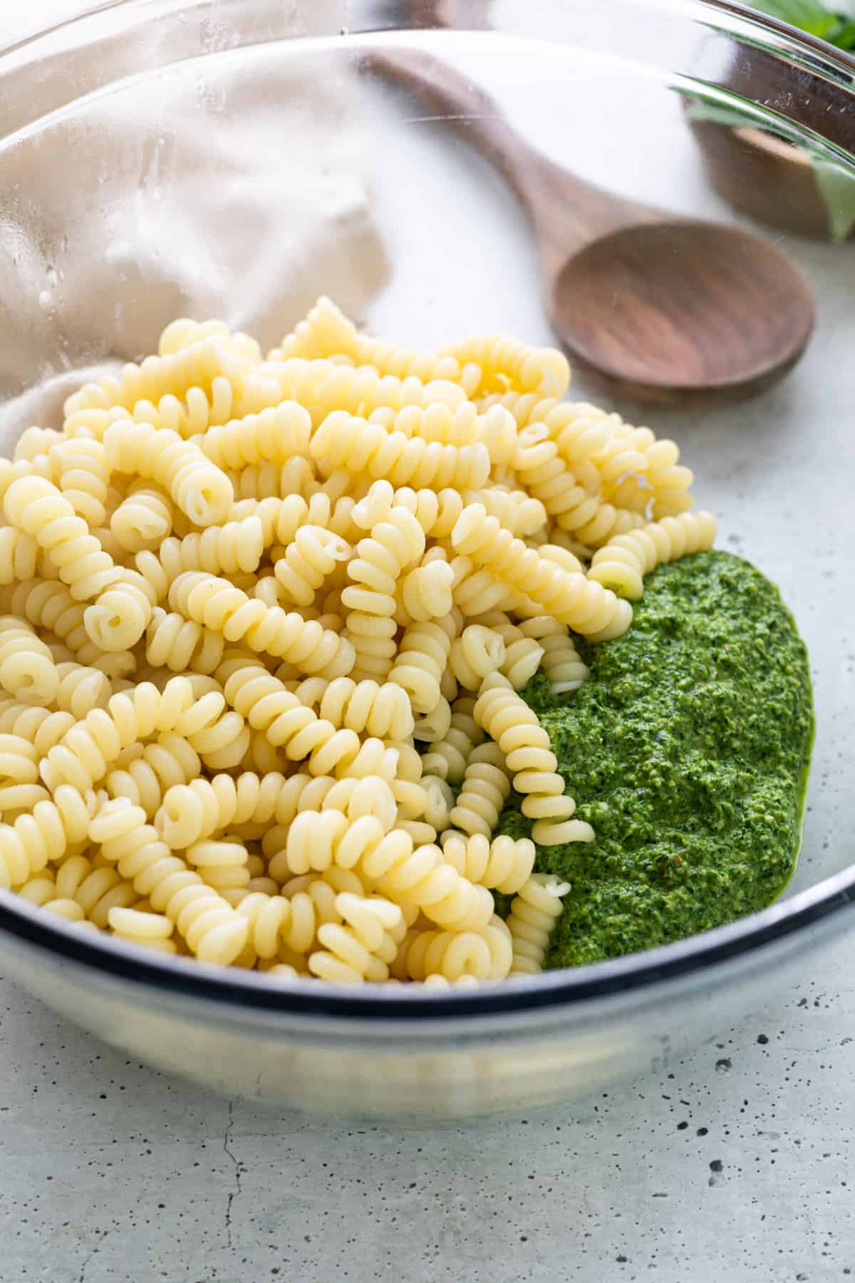 A large bowl of noodles and spinach pesto.