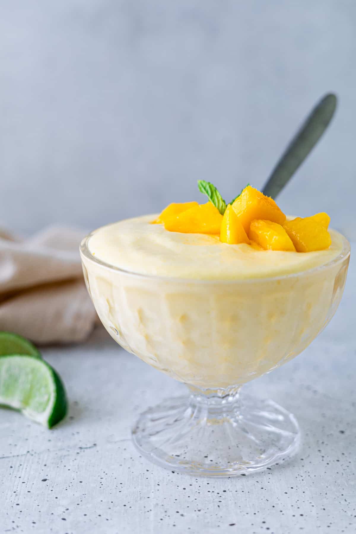 Mango mousse in a dessert glass with fresh mango pieces.