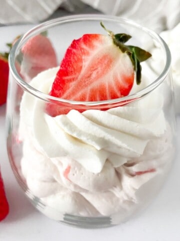 Strawberry cheesecake fluff with whipped cream and fresh strawberries in a glass.