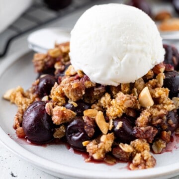 A small plate of cherry crumble with a scoop of ice cream on top.