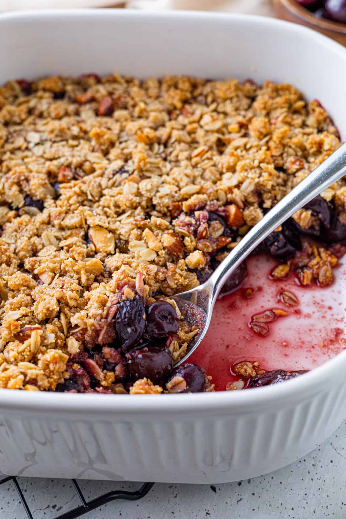 A pan of cherry crumble with a spoon.