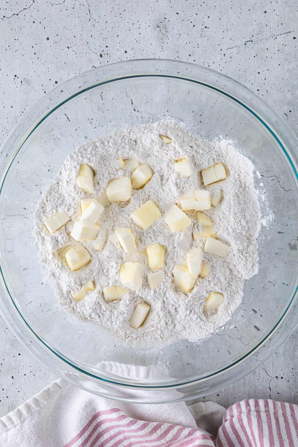 A bowl of flour with diced butter added to it.