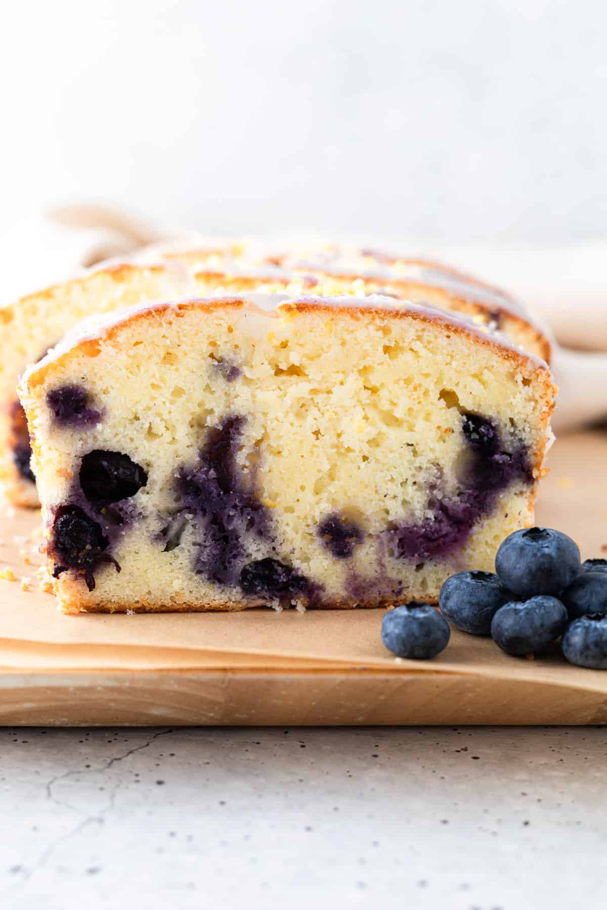 A slice of blueberry pound cake with fresh blueberries.