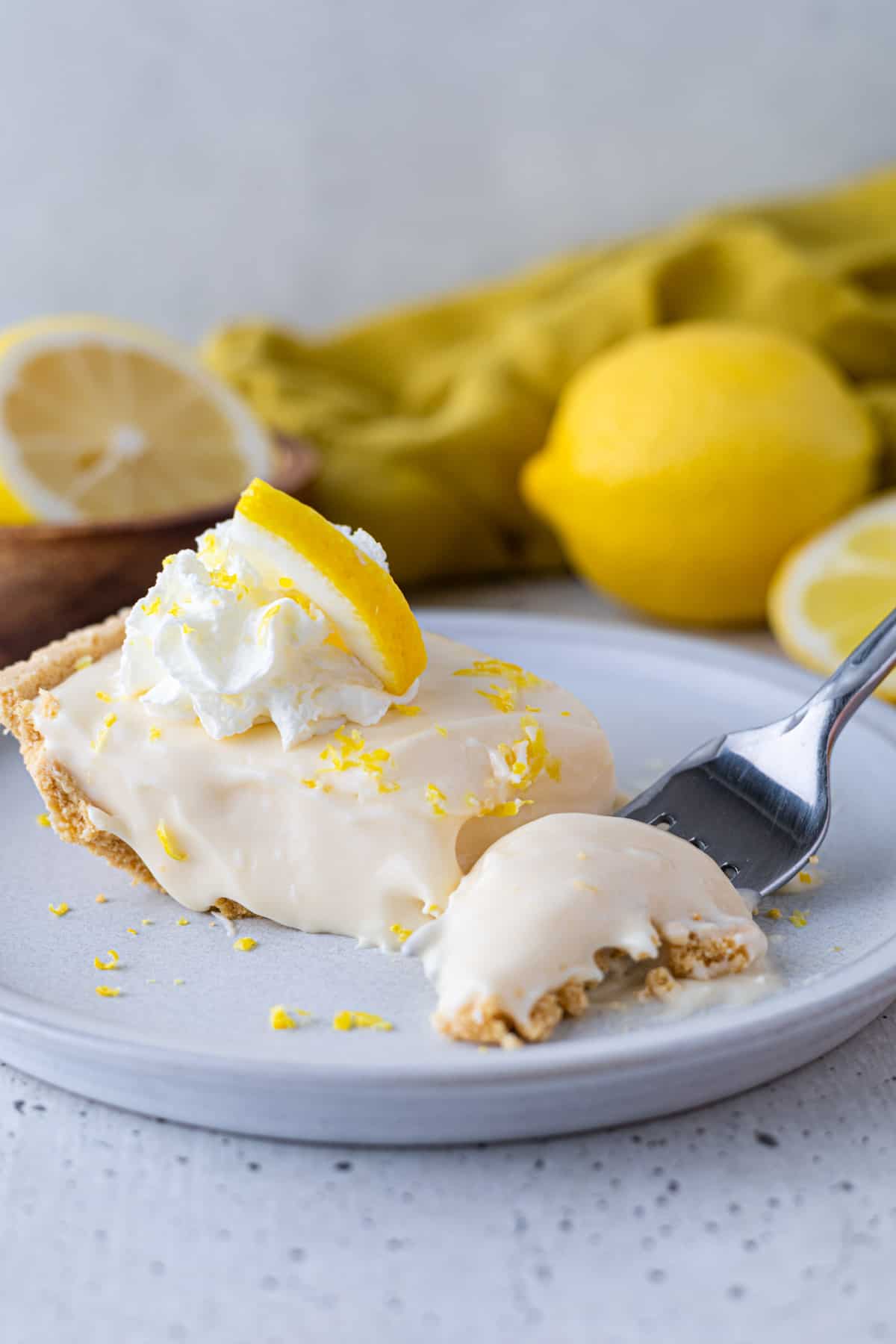 A slice of lemon pie with a bite taken out of it.