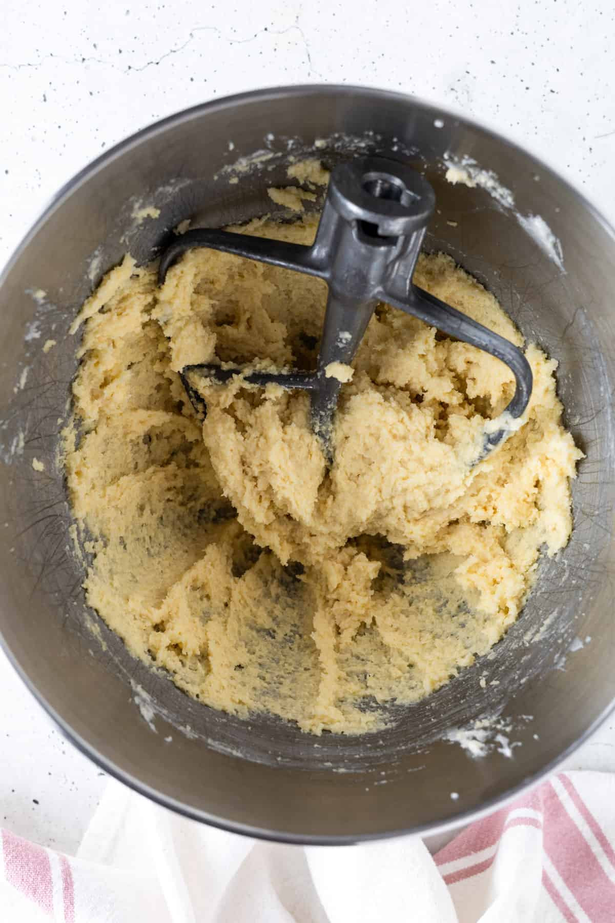 The butter-sugar mixture with almond flour mixed in a bowl with a paddle attachment.