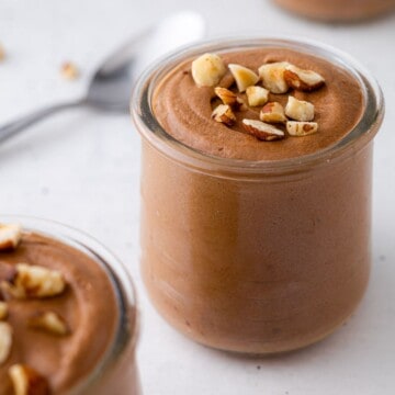 A jar of Nutella mousse with chopped hazelnuts.