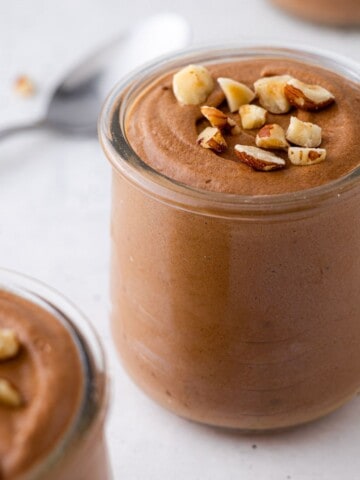 A jar of Nutella mousse with chopped hazelnuts.