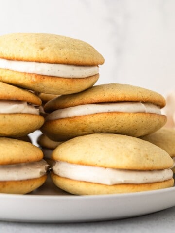 A stack of vanilla whoopie pies on a plate.