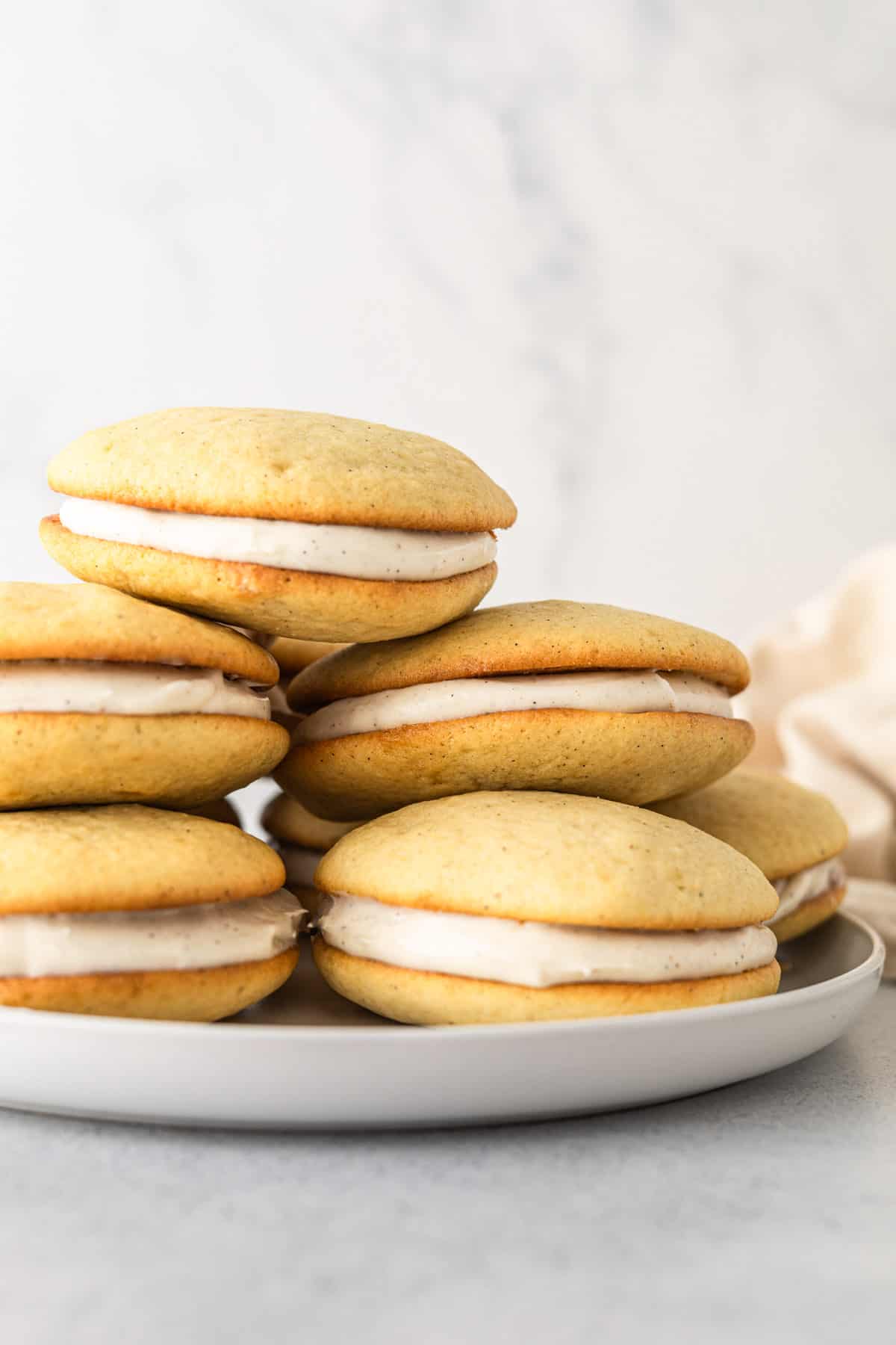 A stack of vanilla whoopie pies on a plate.