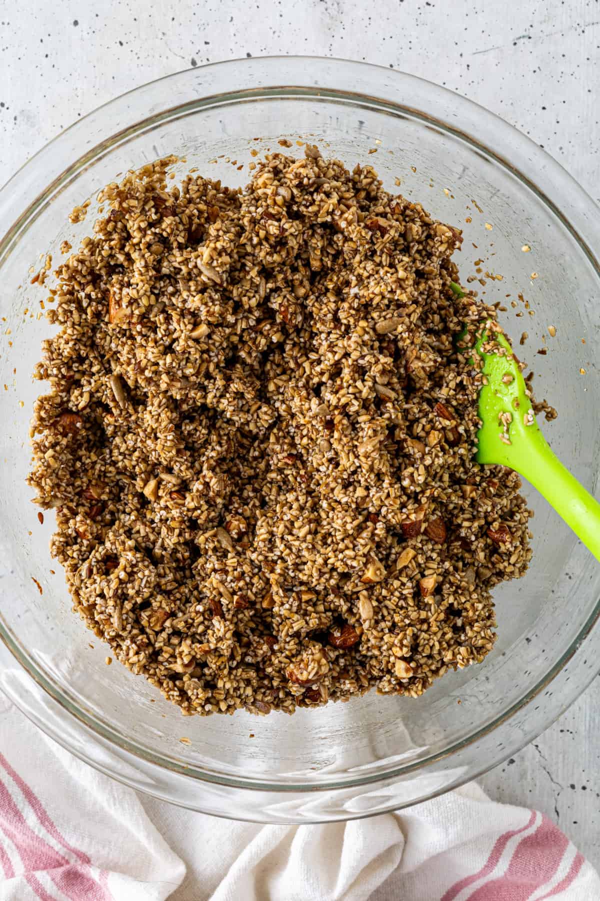 A bowl of steel cut oat granola mixture with a rubber spatula.