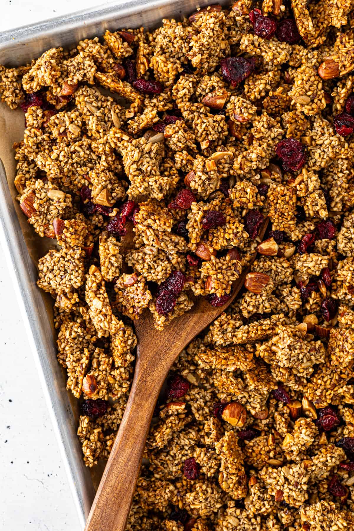 A tray of granola with a wooden spatula.